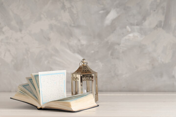 Koran with fanoos on wooden table against white grunge background. Ramadan celebration