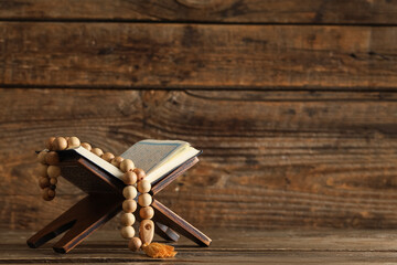 Koran with tasbih on wooden background. Ramadan celebration