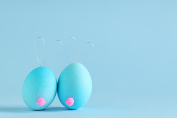 Funny bunnies made of Easter eggs on color background