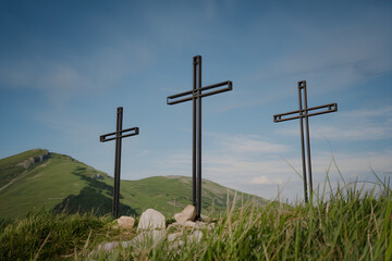 Three Crosses on a Hill Symbolizing Easter, Resurrection, and Christian Faith Under a Blue Sky with Green Grass – Religious Symbol of Hope, Salvation, and Jesus Christ’s Sacrifice