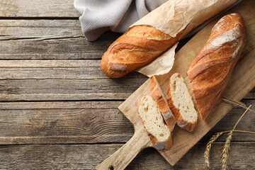 Fresh baguettes and spikes on wooden table, flat lay. Space for text
