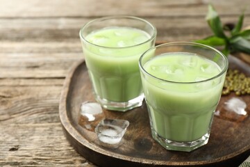 Fresh mung bean juice with ice in glasses on wooden table, closeup. Space for text
