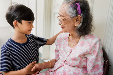 An Indonesian boy greeting his grandmother with a handshake. Concept of good manners when visiting elderly people.