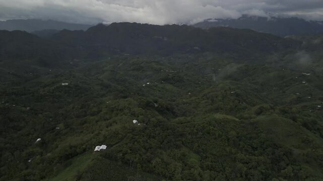 Drone orbits to the right high over forested green valley on a cloudy afternoon in Semuc Champey, Guatemala