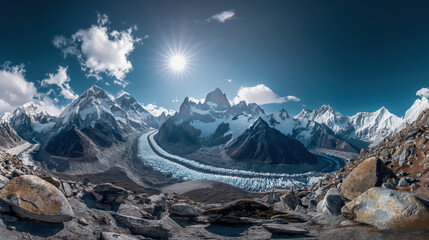 Dramatic wide-angle view of a glacial valley in the Himalayas, with sunburst over jagged mountain peaks.
