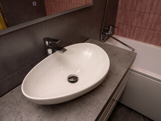 A white sink with a silver faucet sits on a grey countertop