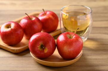 Red apple fruit and apple cider in glass on wooden background