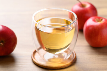 Glass of apple cider and red apple fruit on wooden background