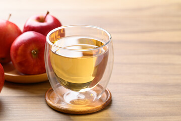 Glass of apple cider and red apple fruit on wooden background