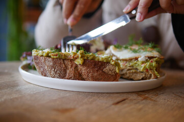 Delicious open-faced sandwich being sliced in a cozy cafe
