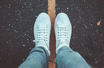 Pair of White Sneakers on a Dividing Line of an Asphalt Pathway in an Urban Environment with Soft Focus Effect