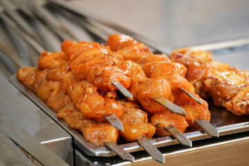 Grilled chicken skewers displayed at a bustling food market