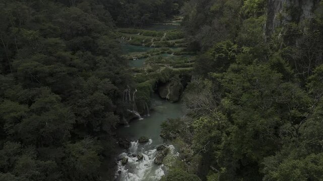 Drone hovers over Cahabon River and pans down over rapids in Semuc Champey, Guatemala