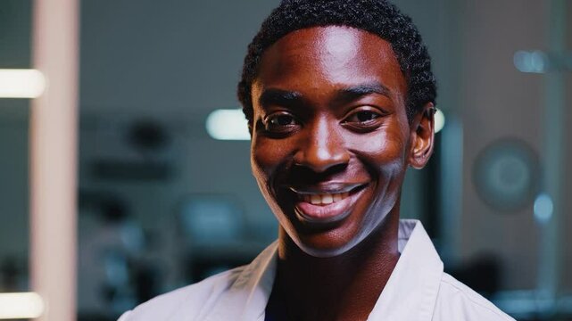 A confident young Black male doctor in a white coat, captured in a medical environment, exuding professionalism and compassion for patient care, ready to make a difference.