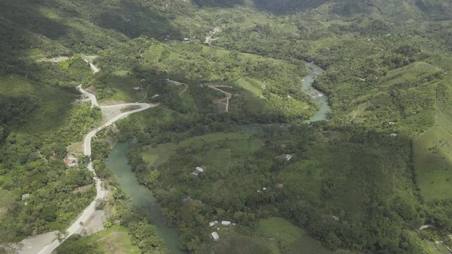 Drone flies north high over the Cahabon River on sunny days with clouds casting shadows on the green hills below in Semuc Champey, Guatemala