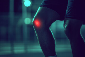  Close-up of athlete holding injured knee or ankle with visible red spot, highlighting pain