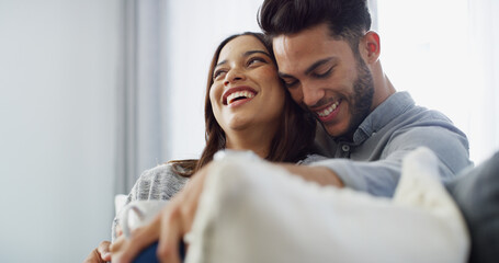 Fototapeta premium Hug, laughing and couple with coffee, house and love in living room with woman, comfortable and bonding. Happy, man and relax with partner in lounge, tea and chilling in home, embrace or relationship