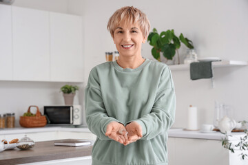Mature woman with hearing aid in kitchen
