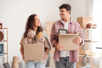 Young couple with boxes for garage sale in room of unwanted stuff