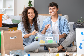 Young couple throwing plastic rubbish in garbage container at home. Waste sorting concept