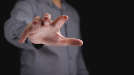 Businessman hand reach out to grab something in black background in concept of seize for opportunity and success.