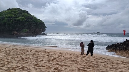 A loving couple enjoys a summer walk on the sandy beach by the ocean under the vast sky