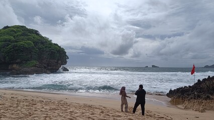 A loving couple enjoys a summer walk on the sandy beach by the ocean under the vast sky