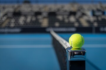 yellow tennis ball sitting on a blue tennis court in summer next to the tennis net and white line