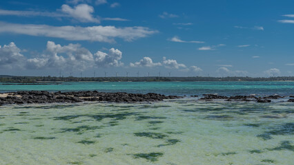 Tropical seascape. Crystal clear turquoise water in the shallows. A pile of volcanic black...
