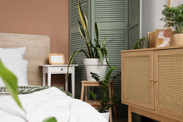 Interior of bedroom with plants, table and folding screen