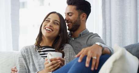 Happy, relax and couple with coffee in home for conversation, bonding and chill together. Living room, dating and man hug woman with drink on sofa for relationship, affection and embrace for love