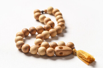 Wooden prayer beads on white grunge background, closeup. Ramadan celebration