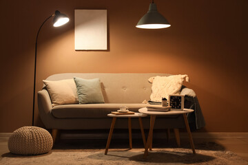 Comfortable sofa, coffee table and glowing lamps in interior of stylish living room