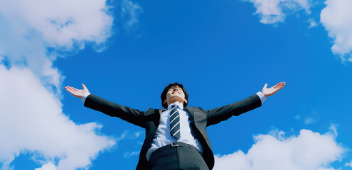 自由と挑戦、青空に手を伸ばす若手ビジネスマン