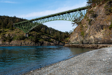 This image features a green bridge arching gracefully over a picturesque coastal landscape, accentuating the harmony between human engineering and natural beauty.