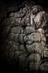 This image showcases stunning stalactite formations hanging from a rocky ceiling in a dimly lit cave, highlighting their unique textures and shadows.
