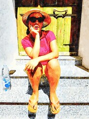 Young woman sitting on steps of an entrance relaxing during a sunny summer day.