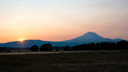 A stunning view of a sunset illuminating a silhouette of snow-capped mountains, creating a serene and peaceful atmosphere in nature’s landscape.