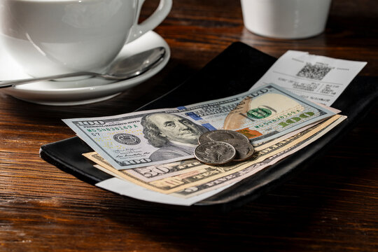 American money in a tip tray when paying a bill after eating at a restaurant, closeup. Paying for your bill tab at a restaurant cafe with cash money