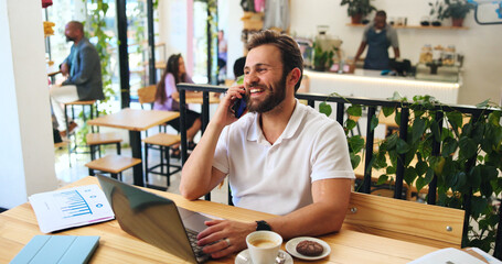 Phone call, laptop and smile with man in cafe for journalist, remote worker and research. Planning, editor feedback and networking with male person in coffee shop for article writing and update
