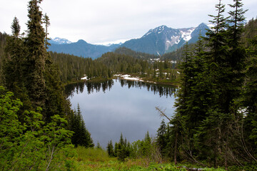 A serene mountain lake surrounded by lush green trees, reflecting the mountains above, presenting an idyllic destination for relaxation and reconnecting with nature.