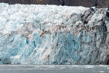 A close-up view of a glacier showcasing the intricate textures and colors of thawing ice,...