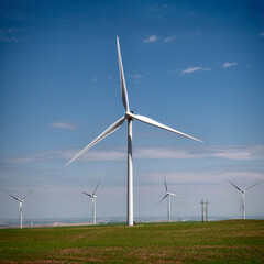 A stunning view of modern wind turbines standing tall against a bright blue sky, symbolizing...