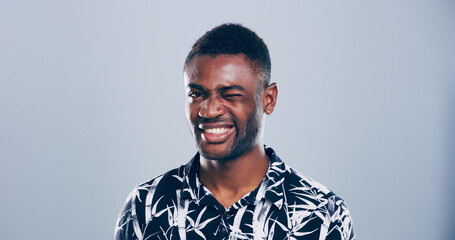 Black man, happy and face with wink in studio portrait, sign or emoji for secret, flirt or joke by...