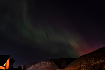 The stunning aurora borealis fills the night sky with vivid green and violet hues, captivating the viewer as it dances over mountains in this breathtaking natural display.