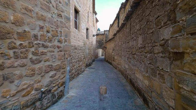 Narrow alley with very old stone walls and medieval arches in the streets of Baeza, Jaen, Spain.