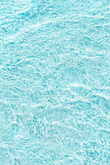 Crystal clear blue sea water surface with sunlit ripples tropical nature vertical background. Rippled effect on sand beach, backdrop with sunlight reflection underwater, transparent aqua texture.