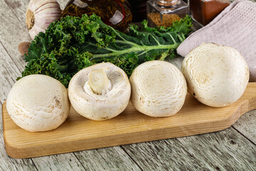 White champignon mushrooms heap over board