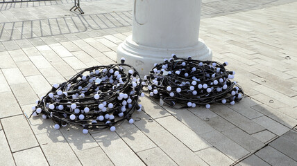 Garlands of decorative bulbs coiled on the ground before being hung for site decoration during a...