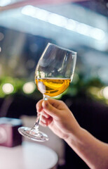 The girl holds a glass of white wine in her hand
